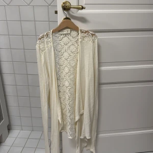Vit spetskofta från Abercrombie & Fitch - Säljer en elegant vit spetskofta från Abercrombie & Fitch. Koftan har ett vackert spetsmönster och långa ärmar, perfekt för att lägga till en romantisk touch till din outfit. Passar bra till både vardag och speciella tillfällen. 🌸
