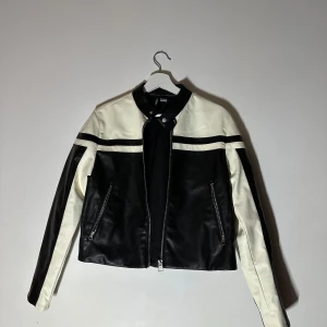 Skinnjacka  - Snygg svart och vit skinnjacka från Zara med dragkedja framtill och två fickor med dragkedjor. Jackan har en stilren design med kontrasterande färger och långa ärmar. Perfekt för en cool look.🥰🥰🥰