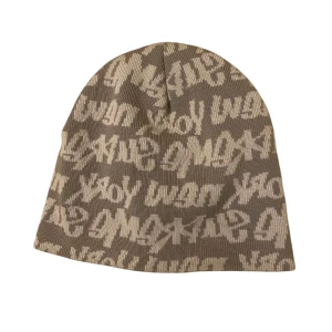 Beige mössa med graffiti från Supreme - Snygg beige mössa från Supreme med ett coolt graffiti-mönster i vitt. Tillverkad i 100% bomull, perfekt för att hålla stilen året runt. En unik accessoar för den modemedvetna.