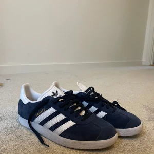 Adidas Gazelle i blå mocka - Adidas Gazelle sneakers i blå mocka med vita detaljer och snörning. Använd fåtalgånger men fortfarande i nyskick.