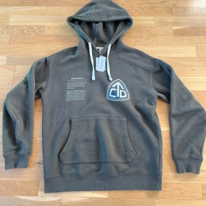 Grön hoodie från Woolrich - Säljer en grön hoodie från Woolrich med en stor ficka framtill och en cool logga på bröstet. Den har en justerbar huva med vita snören och ribbade muddar vid ärmslut och nederkant. Perfekt för en avslappnad stil! Nypris: 2000 kr 