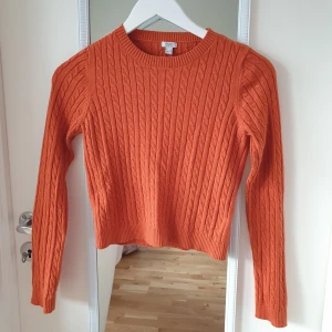 Orange stickad tröja från OVS - Säljer en snygg orange stickad tröja från OVS. Tröjan har ett klassiskt flätmönster och långa ärmar. Perfekt för kyligare dagar. Passar bra till jeans eller kjol för en avslappnad look. 🧡