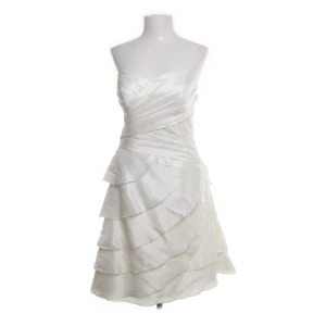 Vit axelbandslös klänning med volanger /studentklänning  - Vit studentklänning klänning – supersöt och elegant  Storlek: 40 Skick: Jätte bra – Tyvärr aldrig använd men köpt på Sellpy så begagnad Märke: Symphony of Venus  Köpte för min studenten men den var för stor för mig eftersom jag bär en M. Enkel vit  klänning utan remmar, "hearth necklace" och lager volangdetalj. Känns som väldigt bra kvalitet. Perfekt för bröllop, studentklänning, fester eller speciella tillfällen.  Köp gärna innan de 25/2💌 💓 