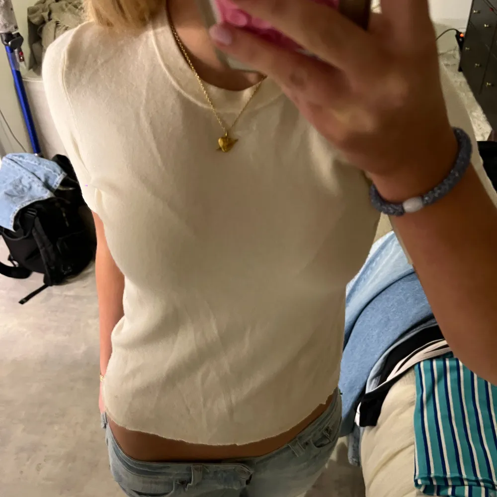 Säljer en stilren beige topp med korta ärmar. Toppen har en enkel design och är perfekt för en avslappnad look. Den är tillverkad i ett mjukt material som känns skönt mot huden.. Yläosat.