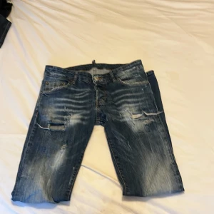 Blå jeans från Dsquared2 - Snygga blå jeans från Dsquared2 med slitna detaljer och en cool tvätt. De har en klassisk femficksdesign och knappgylf. Perfekta för en avslappnad stil med en touch av edge.