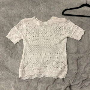Vit stickad topp med spetsdetaljer - Säljer en söt vit stickad topp med vackra spetsdetaljer. Toppen har korta ärmar och ett fint mönster som ger en romantisk känsla. Perfekt för vår och sommar! 🌸