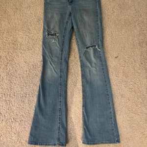 Ljusa jeans med slitningar från Only - Snygga ljusa jeans från Only med slitningar på låren och knäna. De har en bootcut-stil och är perfekta för en avslappnad look. Jeansen har en klassisk femficksdesign och stängs med dragkedja och knapp.