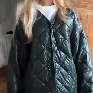 Grön quiltad jacka från Gina Tricot - Snygg grön quiltad jacka från Gina Tricot med en modern look. Jackan har en v-ringad design och långa ärmar, perfekt för att hålla stilen i övergångsperioder. Den är lätt och bekväm att bära, vilket gör den till ett mångsidigt tillskott i garderoben.