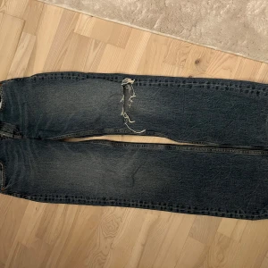 Blå lågmidjade bootcut jeans från Zara  - Säljer ett par lågmidjade bootcut jeans från Zara med snyggt hål vid knät.