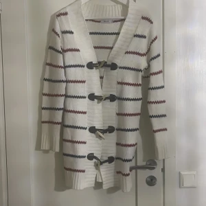 Randig kofta från Rut m.fl. - Säljer en superfin randig kofta från Rut m.fl. i storlek XS. Den är vit med ränder i rött och svart, och har snygga knappar framtill. Perfekt för höst och vår, och den är i mycket bra skick. Passar både till vardags och lite finare tillfällen!