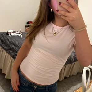 Ljusrosa tight topp - Säljer en ljusrosa tight topp i mycket bra skick. Den är ärmlös och perfekt för sommaren. Toppen är enkel och stilren, vilket gör den lätt att matcha med olika outfits. Perfekt för både vardag och fest!
