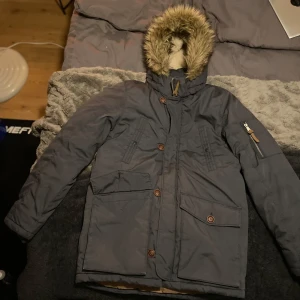 Grå parkajacka från H&M - Säljer en grå parkajacka från H&M i storlek EUR 164. Jackan har en mysig pälsfodrad huva och knappar framtill. Perfekt för kalla höst- och vinterdagar. Den har flera praktiska fickor och är i hyfsat bra skick förutom att högra sido fickan saknar knapp. Bara att höra av sig vid frågor 😇