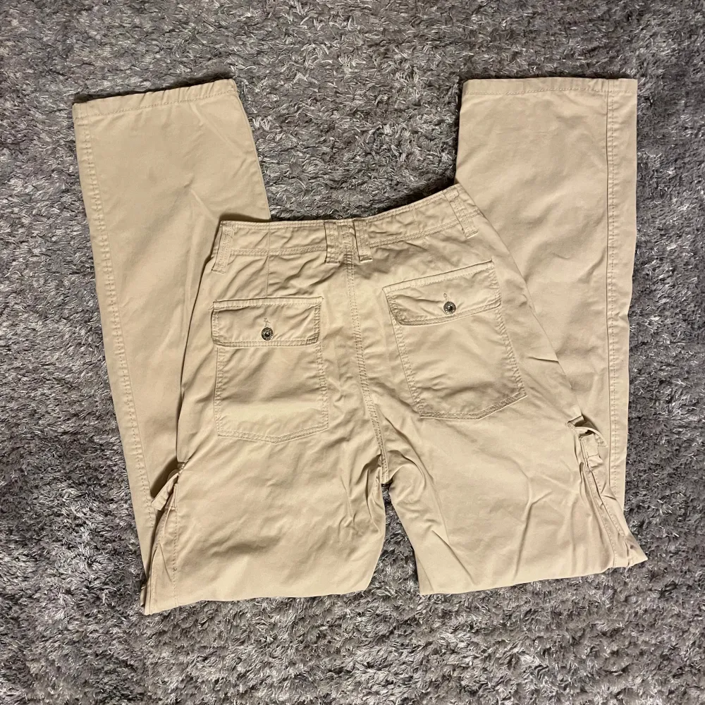 Säljer ett par snygga beige cargobyxor från Bershka i storlek 32/S. Byxorna har flera praktiska fickor och en avslappnad passform. Perfekta för en casual look eller äventyr utomhus. De är i bra skick och redo för nya äventyr!. Jeans & Byxor.