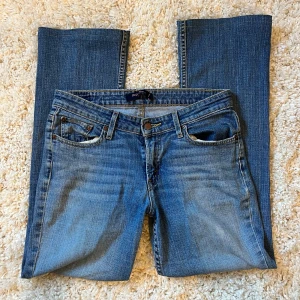 Blå jeans från Levis - Säljer ett par snygga blå jeans från Levis  i modellen superlow 518. De är lågmidjade och har en klassisk femficksdesign med dragkedja och knapp. Perfekta för vardagsbruk och passar till det mesta i garderoben! Passar någon runt 165cm, midjemåttet är 38cm