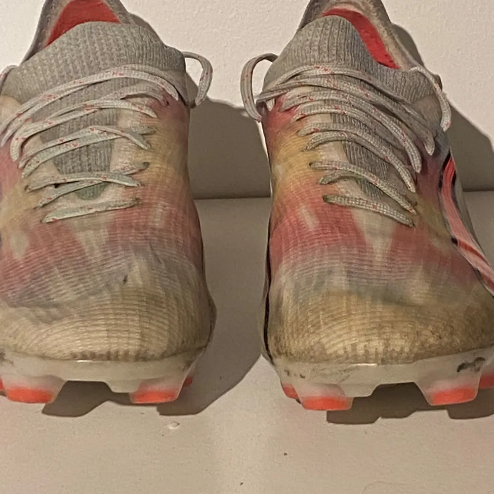Säljer ett par fotbollsskor från Puma i bra skick. Skorna är i en vit och röd färgkombination med svarta detaljer. De har snörning och är perfekta för fotbollsträning eller match. Sulan har bra grepp och är designad för att ge stabilitet på planen. Konstgräss och normal gräs. Kengät.