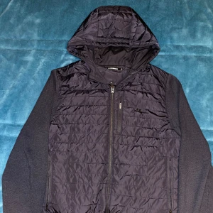 J.Lindeberg cardigan - Säljer nu min  marinblåa cardigan från j.lindeberg . Den har en dragkedja framtill och är långärmad. Perfekt för höst och vinter, håller dig varm och bekväm. Passar både till vardags och fest. Nypris 3500, mitt pris 700, priset kan diskuteras vid snabb affär 