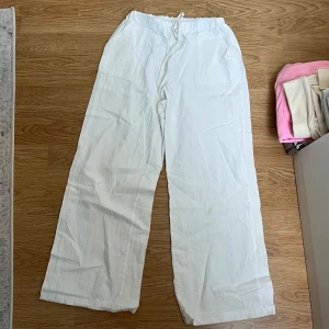 Vita vida byxor - Säljer ett par vita vida byxor i mycket bra skick. De är högmidjade med en bekväm elastisk midja och har en loose passform. Perfekta för sommardagar eller avslappnade tillfällen. Materialet känns lätt och luftigt, vilket gör dem idealiska för varmare väder.
