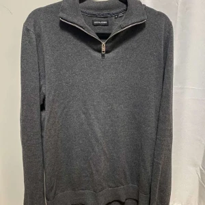 Grå halv zip från Jack & Jones - Säljer en stilren grå tröja från Jack & Jones i mycket bra skick. Perfekt för vardagsbruk eller en avslappnad dag ute.