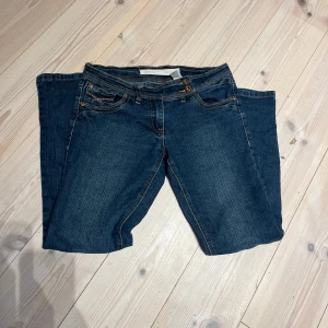 Blå jeans med dubbla knappar - Säljer dessa super fina mörkblåa lågmidjade jeans med cool knäppning från next petite då de tyvärr är lite för korta i benen för mig. Det står ingen storlek i jeansen men de passar bra i midjan för mig som vanligtvis använder XS/S. Jag är 161cm och de är lite för korta för mig. Jeansen har inga täcken på användning eller slitage. Pris kan diskuteras