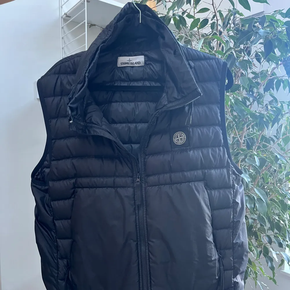 Säljer en snygg svart dunväst från Stone Island. Västen har en dragkedja framtill och är perfekt för höst och vår. Den är i mycket bra skick och har en normal passning.. Jackor.