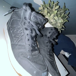 Svarta sneakers från Kappa - Säljer ett par svarta sneakers från Kappa i bra skick. De har en vit sula och klassisk snörning. Perfekta för vardagsbruk och passar till de flesta outfits. Några små märken finns på ovansidan, men inget som stör funktionen.