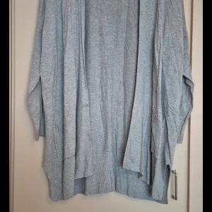 Grå kofta från Atmosphere - Mysig grå kofta från Atmosphere i storlek L. Perfekt för kyliga dagar med sin långa och bekväma passform. Den har långa ärmar och en ribbad kant nedtill som ger en stilren look. Passar både till vardags och lite finare tillfällen.