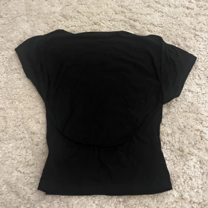 Svart kortärmad topp - Säljer en stilren svart topp med korta ärmar och öppen rygg. 