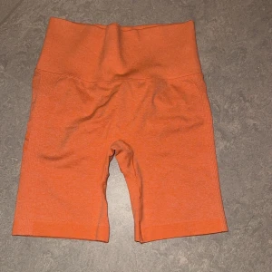 Träningsshorts - Säljer 3 par träningsshorts i olika färger. Ett par är i en härlig orange färg och det andra i en stilren grå, den tredje är korall grön/blå. Alla 3 har högmidja och har en tight passform, perfekta för gymmet eller löprundan. Materialet är stretchigt och bekvämt, vilket gör dem idealiska för träning. Passa på att uppdatera din träningsgarderob! Säljs för 80kr tillsammans 