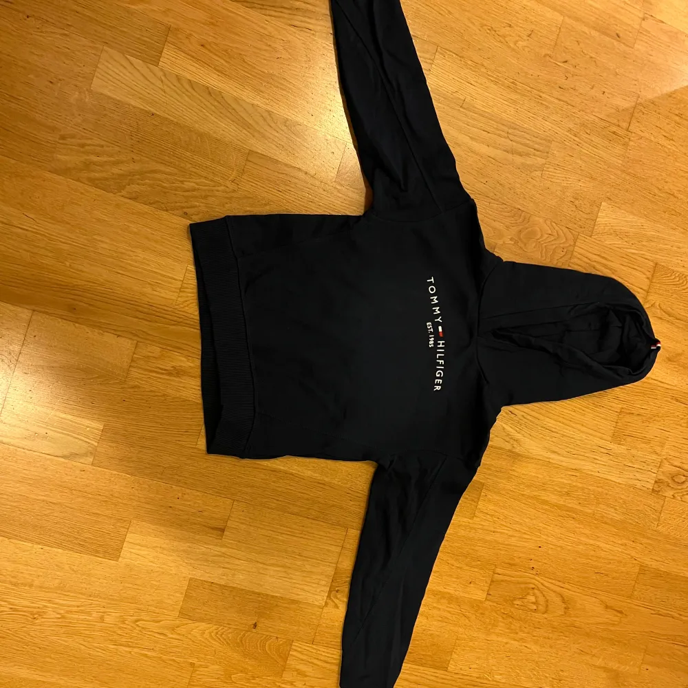 Säljer en snygg marinblå hoodie från Tommy Hilfiger i storlek 140 (barnstorlek). Den har en klassisk design med loggan tryckt på framsidan och en bekväm huva. Perfekt för både vardag och chill. Passar bra till jeans eller joggers! Nypris 695kr. Använd ett fåtal gånger. Inga fläckar eller skador. Pris går att diskuteras! . Neuletakit & Villapaidat.