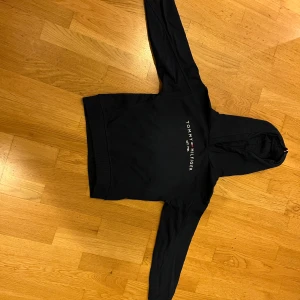 Marinblå hoodie från Tommy Hilfiger - Säljer en snygg marinblå hoodie från Tommy Hilfiger i storlek 140 (barnstorlek). Den har en klassisk design med loggan tryckt på framsidan och en bekväm huva. Perfekt för både vardag och chill. Passar bra till jeans eller joggers! Nypris 695kr. Använd ett fåtal gånger. Inga fläckar eller skador. Pris går att diskuteras! 