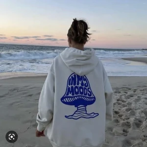 Cream Vit hoodie med blått tryck - Säljer en supermysig vit hoodie med ett coolt blått tryck på ryggen  'IN MY MOODS'💙 Perfekt för chill dagar. Den har en skön passform och en stor huva för extra komfort. Storlek L, men (brukar ha xs/s) ville att den skulle sitta som tjejer på första bilden som har L. Köpt för 2000kr, populär och svår att få tag i💙aldrig använd!