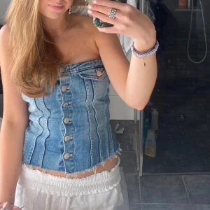Jeans korsett - Säljer en snygg populär jeans korsettopp i blått med knappar framtill. Toppen har en tight passform. Jättefint skick utan defekter💕