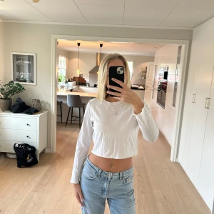 Långärmad vit tröja - Långärmad vit tröja, lite cropad i modellen, från Pieces. Små ”volanger” nertill på tröjan. Storlek L men skulle säga att den är stor i storleken och passar S/M också. Aldrig använd så i nyskick.💕