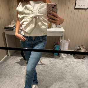 Vit axelbandslös topp med stor rosett - Säljer en superfin vit axelbandslös topp med en stor rosett framtill. Slutsåld från Kappahl. Köpt för 500 och säljer endast för bra pris då jag tycker mycket om den. Använd en gång.