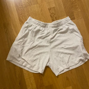 Vita frottéshorts - Säljer ett par superbekväma vita shorts i frotté. Perfekta för en avslappnad dag hemma eller på stranden. De har en elastisk midja för extra komfort. Passar perfekt till sommaren!