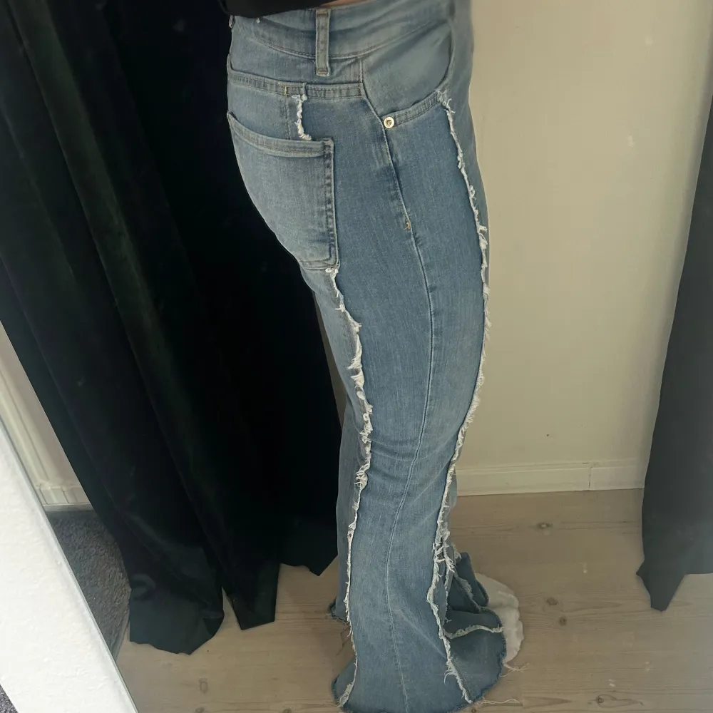 Säljer ett par snygga blå bootcut jeans med fransdetaljer längs benen. De är lågmidjade och bootcut. . Jeans & Byxor.