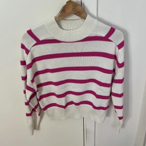 Vit och rosa randig tröja från Amisu - Säljer en superfin vit tröja med rosa ränder från Amisu. Den är stickad och har en skön, normal passform. Perfekt för både vår och höst! Tröjan har långa ärmar och en rund halsringning. Den är i mycket bra skick och redo för nya äventyr. 🌸