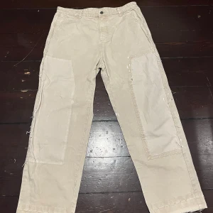 Beige byxor från Zara - Säljer ett par beige byxor från Zara i storlek 44. Byxorna har en avslappnad passform med raka ben och är tillverkade i ett slitstarkt material. Perfekta för en casual look eller vardagsbruk. De har praktiska fickor och en knappgylf.
