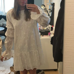 Studentklänning  - Säljer en superfin studentklänning som är för många svår att få tag i. Den är använd en gång, när jag sprang ut och jag verkligen älskade den. Det är en vit klänning med blommigt mönster. Den har långa ärmar med volangdetaljer och en söt volangkant längst ner. Klänningen är i mycket bra skick och har en normal passform. Nypris är 799.
