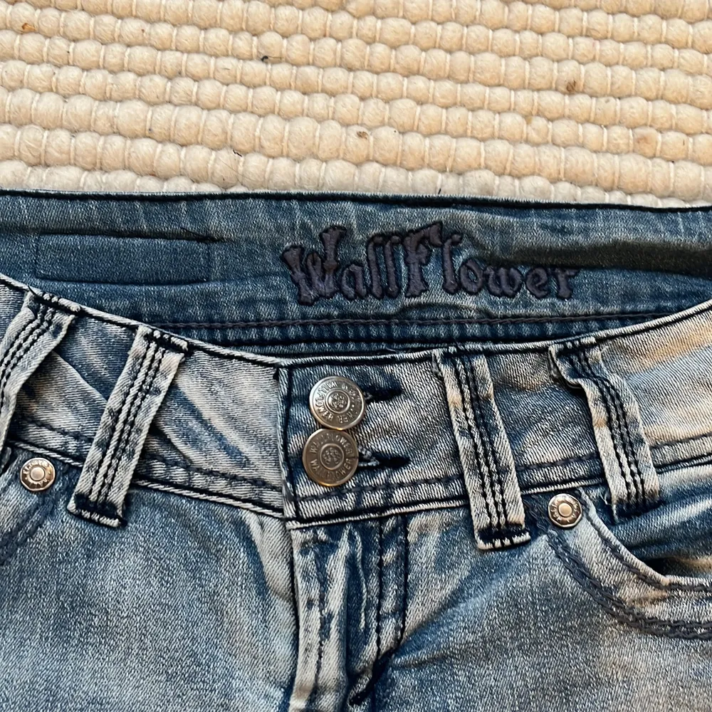 Snygga trendiga grå bootcut jeans från Wallflower. De har en cool tvättad look och dubbla knappar i midjan. Bakfickorna har snygga detaljer. Midjemåttet: ca 76 Innerbenslängden: ca 79 . Jeans & Byxor.