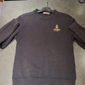 Mörkblå tröja från Morris - Säljer en snygg mörkblå tröja från Morris med broderad logga på bröstet. Tröjan är i bra skick och perfekt för både höst och vinter. Den har en klassisk rund hals och ribbade muddar för en bekväm passform. Är storlek L men sitter mer som en M. Priset går att diskutera vid snabb affär 