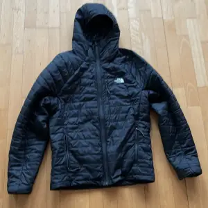 Säljer en svart quiltad jacka från The North Face i mycket bra skick. Den har en praktisk huva och dragkedja framtill. Perfekt för kyliga höst- och vårdagar. Jackan är lätt och bekväm, idealisk för både vardag och utomhusaktiviteter. Passa på att fynda denna jacka!