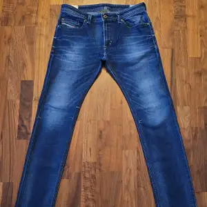 Säljer ett par snygga blå jeans från Diesel i modellen Thavar. De har en slim-skinny passform och är i stretchmaterial för extra komfort. Perfekta för både vardag och fest! Jeansen har en klassisk femficksdesign och en snygg tvättad look.