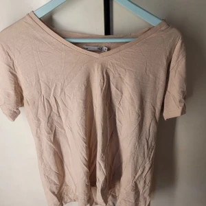 Rosa t-shirt från 157 - Säljer en enkel och stilren rosa t-shirt från 157 i storlek M. Den har en v-ringad hals och korta ärmar, perfekt för vardagsbruk. Materialet känns mjukt och bekvämt, idealiskt för både vår och sommar. Passar bra till jeans eller kjol för en avslappnad look.