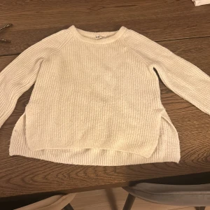 Vit stickad tröja från H&M - Mysig vit stickad tröja från H&M i storlek 146/152. Perfekt för kyliga dagar med sin mjuka och bekväma passform. Tröjan har långa ärmar och en rund halsringning. Passar både till vardags och lite finare tillfällen. 🧶✨