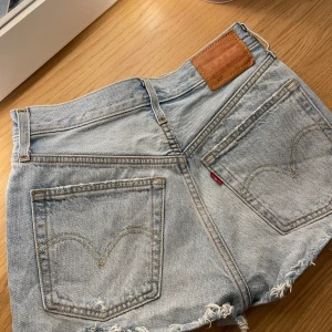 Levi's 501 jeansshorts - Säljer ett par klassiska Levi's 501 jeansshorts i ljusblå denim. De har en snygg fransig kant och är högmidjade för en bekväm passform. Perfekta för sommardagar och festivaler! 🕶️