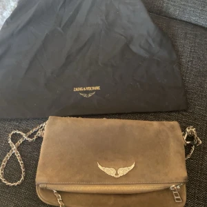 Brun mockaväska från Zadig & Voltaire - Säljer en snygg brun axelväska i mocka från Zadig & voltair✨Den är väll använd därav priset. Finns tecken på användning men fungerar fullt. Skriv frågor mm. Dust bag medkommer