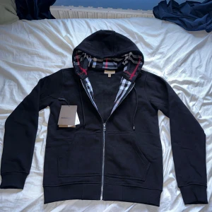 Svart Burberry zipper  - Svart Burberry zipper, den är sprillansny har bara andvända den 1 gång det är därför jag klippt lappen, annars lika bra som ny, storlek: S