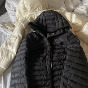 Svart dunjacka från Moncler - Säljer en snygg svart dunjacka från Moncler i mycket bra skick. Jackan har en quiltad design och en praktisk huva. Perfekt för kyliga höst- och vinterdagar. Den har en dragkedja framtill och Monclers logga på ärmen. Supervarm och stilren! Dragkedjan är trasig därav priset. Storlek L men sitter som M