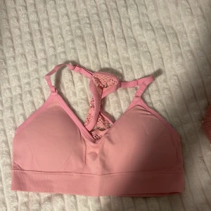 Rosa bralette med spetsdetaljer - Säljer en superfin rosa bralette med spetsdetaljer i ryggen. Den är perfekt för sommardagar eller som ett snyggt lager under en transparent topp. Braletten har justerbara axelband för bästa passform. Använd ett fåtal gånger, så den är i mycket bra skick. Perfekt för dig som vill ha något bekvämt men ändå stilrent! 💖
